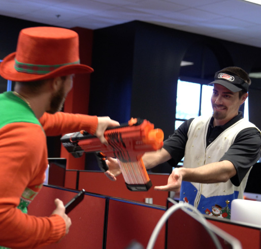 Photo of Chris handing Robert a Nerf toy gun during a steal at our Ugly Sweater White Elephant party